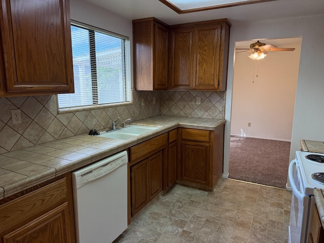 kitchen with white appliances, ceiling fan, tile counters, a sink, and backsplash