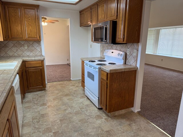 carpeted empty room with baseboards and ceiling fan