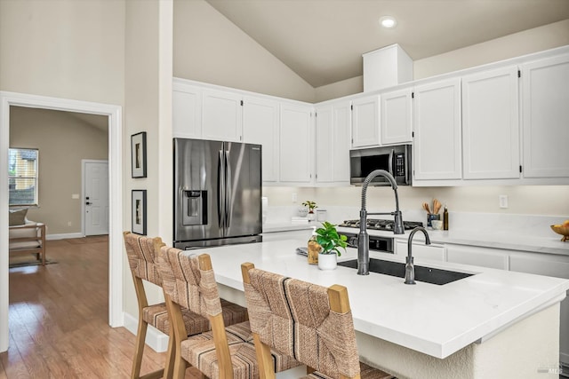 kitchen with light wood finished floors, lofted ceiling, white cabinetry, and stainless steel appliances