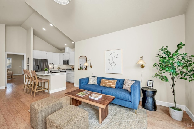 living room featuring baseboards, high vaulted ceiling, and light wood-style flooring