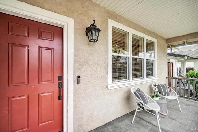 doorway to property featuring stucco siding and covered porch