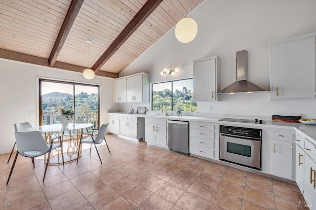 kitchen featuring light countertops, a sink, appliances with stainless steel finishes, wall chimney range hood, and beamed ceiling