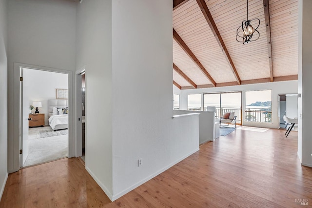 hallway with an upstairs landing, an inviting chandelier, high vaulted ceiling, beamed ceiling, and wood finished floors