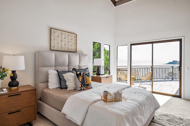 carpeted bedroom with a towering ceiling and access to exterior