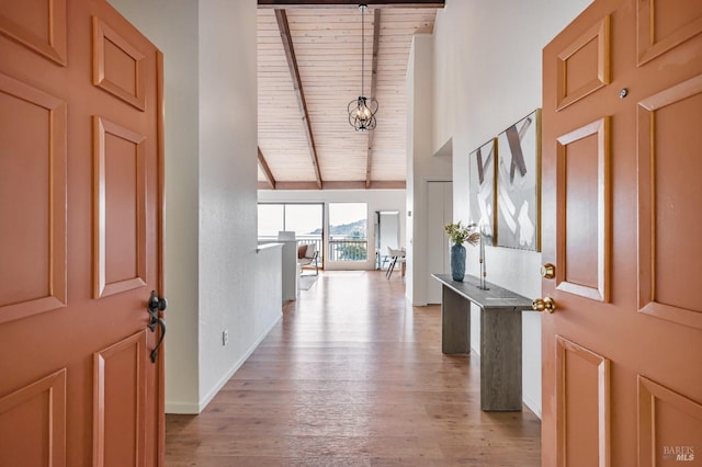 foyer with wooden ceiling, beam ceiling, a chandelier, light wood finished floors, and baseboards