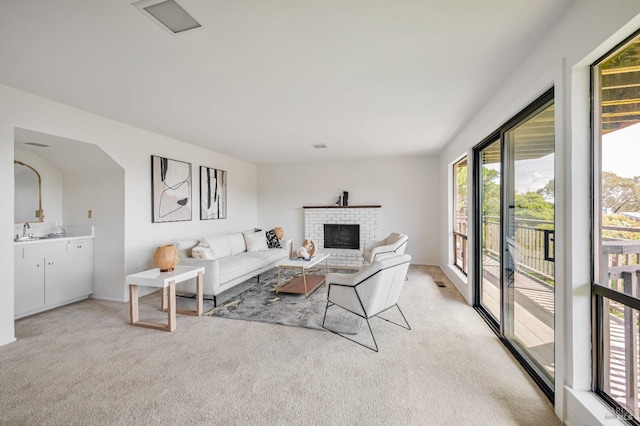 living room with a fireplace, visible vents, and light colored carpet