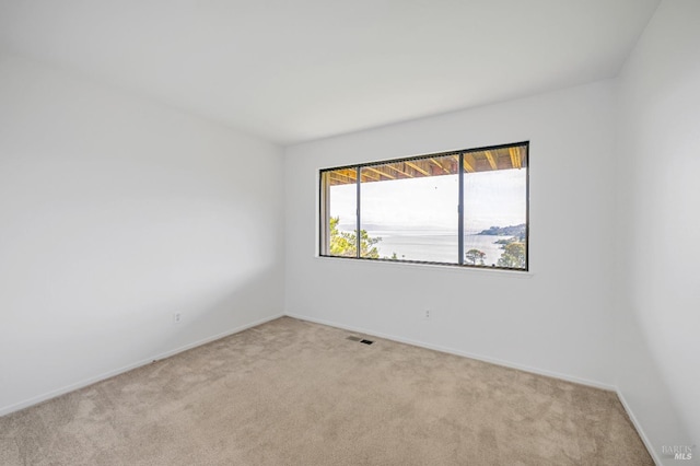 unfurnished room with baseboards, visible vents, and light colored carpet