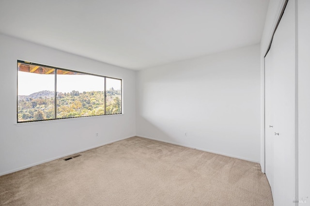 spare room featuring light colored carpet and visible vents