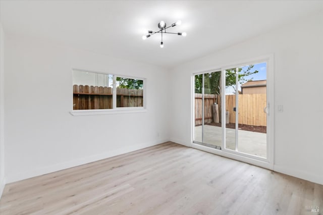 spare room featuring an inviting chandelier, wood finished floors, and baseboards