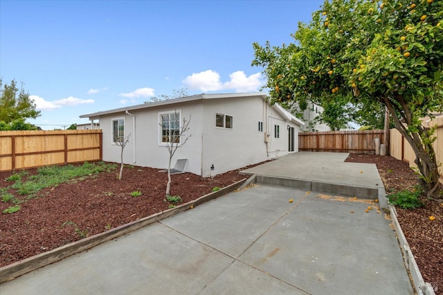 rear view of house featuring stucco siding, a patio, and a fenced backyard