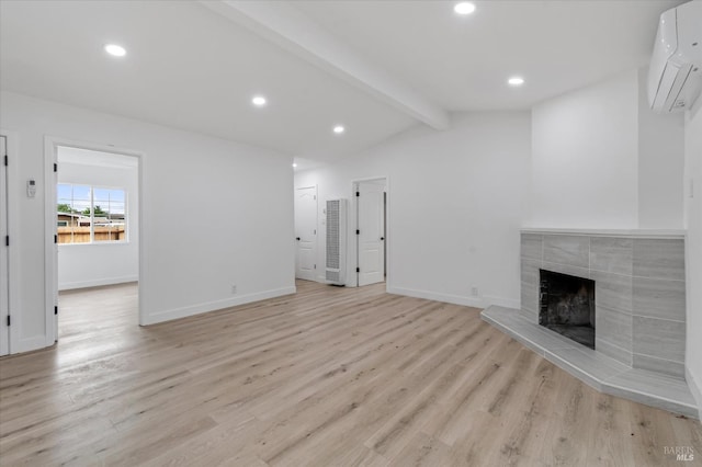 unfurnished living room with a wall unit AC, recessed lighting, light wood finished floors, a fireplace, and vaulted ceiling with beams