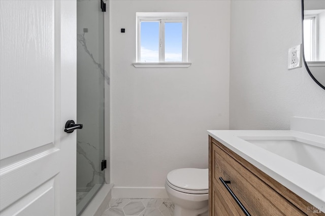 bathroom featuring baseboards, a marble finish shower, plenty of natural light, and vanity