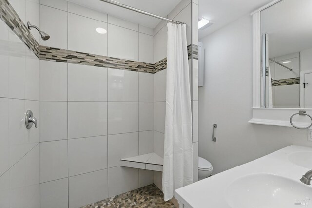 full bath with double vanity, a sink, and a tile shower