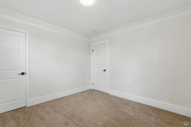 unfurnished room featuring baseboards, ornamental molding, and carpet