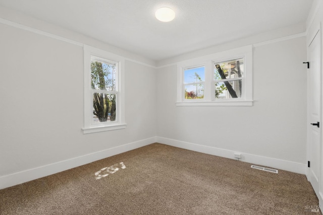 carpeted empty room with baseboards, visible vents, and a healthy amount of sunlight
