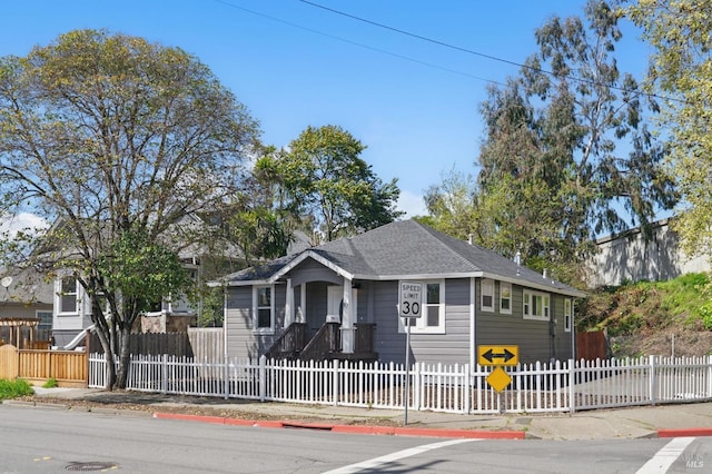 view of front of home featuring a fenced front yard and a shingled roof