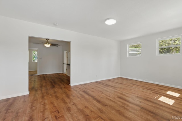 spare room with baseboards, wood finished floors, and a healthy amount of sunlight