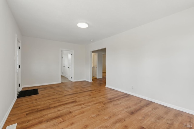 empty room with baseboards, visible vents, and light wood-type flooring