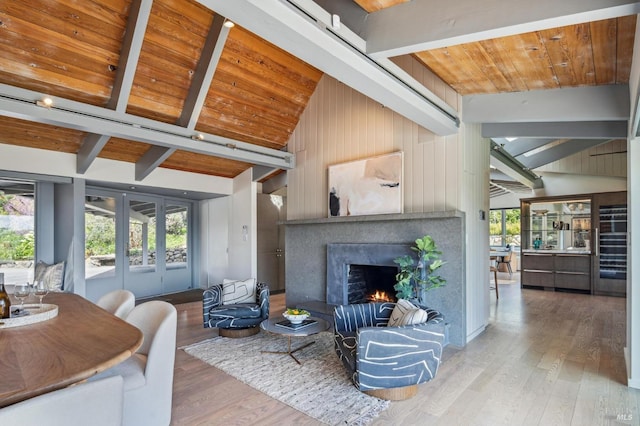 living room with a lit fireplace, wood finished floors, wooden ceiling, and beamed ceiling