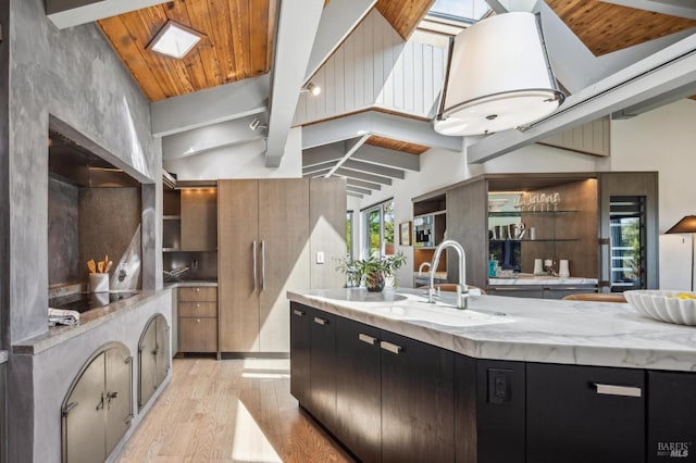 kitchen with wooden ceiling, a sink, black electric cooktop, light wood-style flooring, and dark cabinets