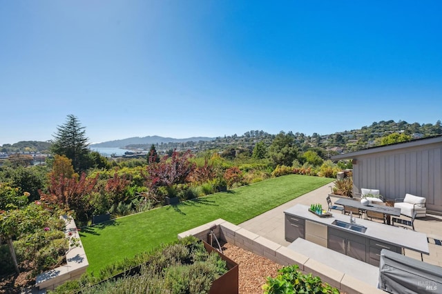 view of yard with outdoor lounge area, a mountain view, a sink, and a patio
