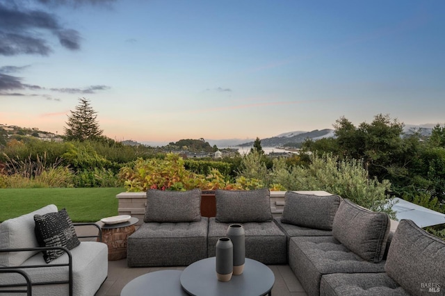 patio terrace at dusk with an outdoor living space, a mountain view, and a yard