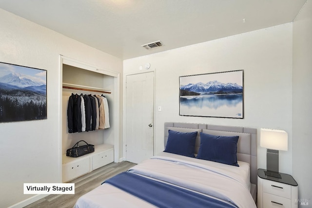 bedroom featuring baseboards, visible vents, light wood finished floors, and a closet