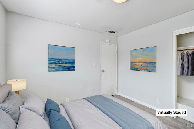 bedroom featuring visible vents, baseboards, wood finished floors, and a closet