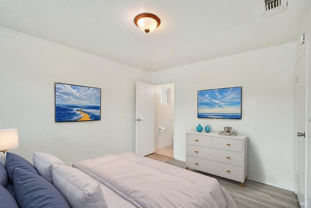 bedroom with baseboards, visible vents, and light wood finished floors