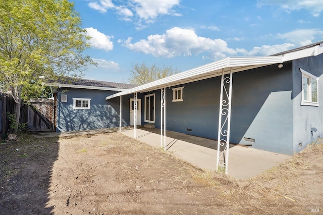 back of property featuring fence, a patio, stucco siding, and crawl space