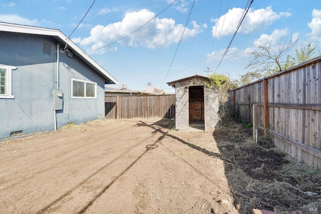 view of yard with a fenced backyard, a shed, and an outbuilding