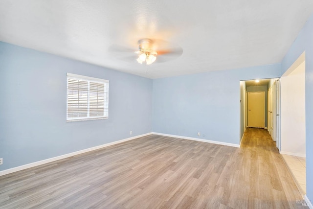 spare room with baseboards, ceiling fan, and light wood-type flooring