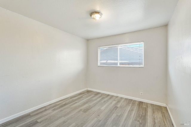 unfurnished room with baseboards and light wood finished floors