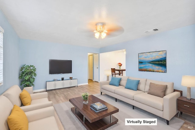 living room featuring visible vents, a ceiling fan, baseboards, and wood finished floors