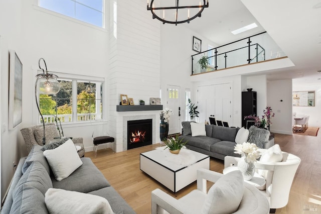 living room with a high ceiling, a fireplace, wood finished floors, and an inviting chandelier