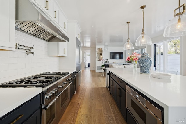 kitchen featuring under cabinet range hood, light countertops, wood finished floors, and high end appliances