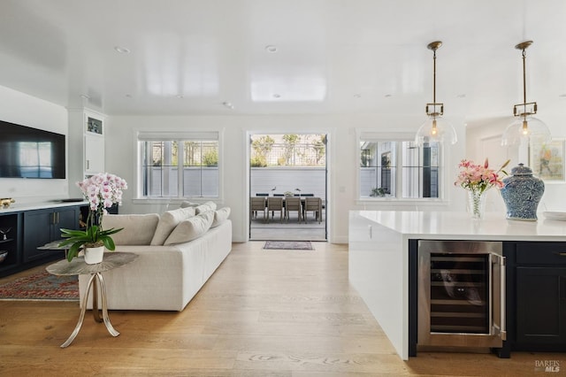 living area with indoor bar, light wood finished floors, recessed lighting, and beverage cooler