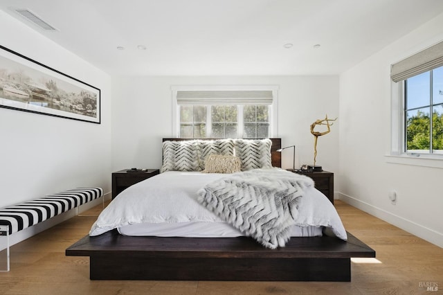 bedroom featuring baseboards, visible vents, and light wood finished floors