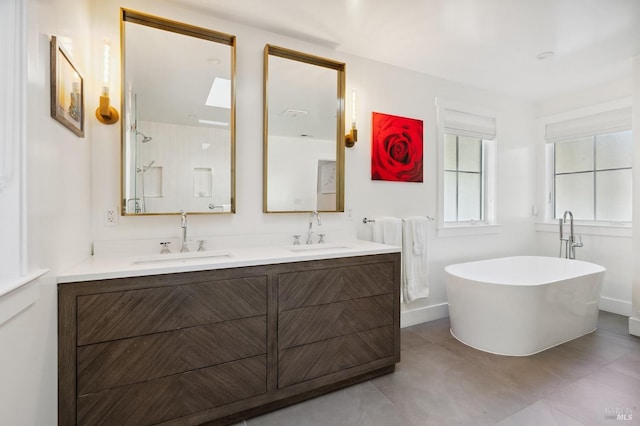 full bath featuring double vanity, a sink, and a freestanding tub