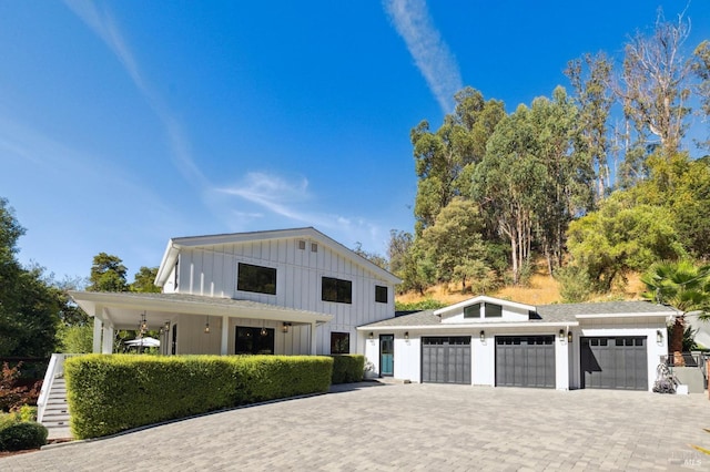 modern farmhouse with stairs, decorative driveway, a garage, and board and batten siding