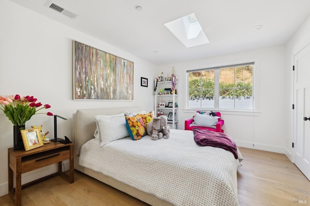 bedroom with baseboards, visible vents, a skylight, and wood finished floors
