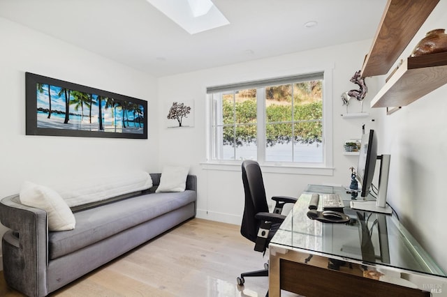 office space with light wood finished floors, baseboards, and a skylight