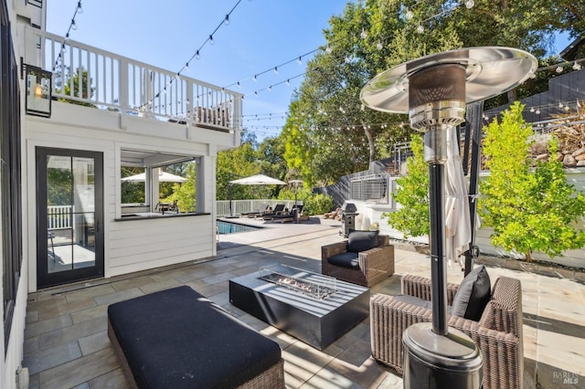 view of patio / terrace featuring an outdoor living space with a fire pit, a balcony, fence, and a fenced in pool