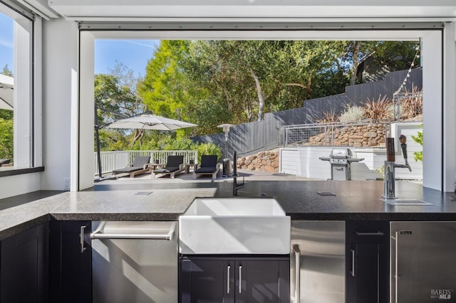 view of patio featuring outdoor wet bar, a fenced backyard, an outdoor kitchen, and grilling area