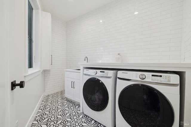 clothes washing area featuring light tile patterned flooring, washer and clothes dryer, cabinet space, and baseboards