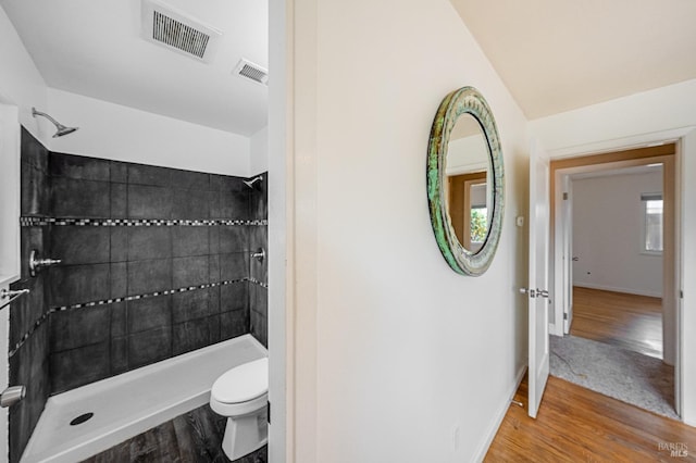 full bath featuring wood finished floors, visible vents, toilet, and tiled shower