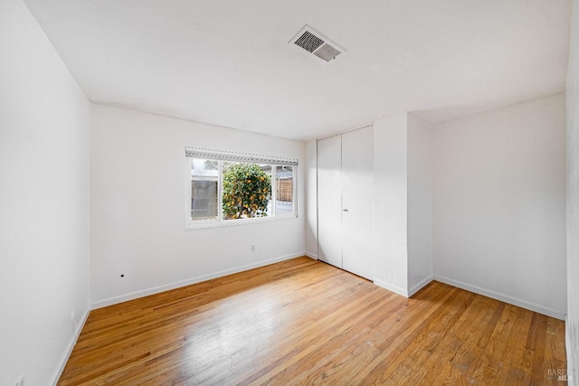 spare room featuring light wood finished floors, baseboards, and visible vents