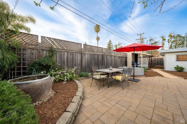 view of patio featuring outdoor dining area, an outdoor structure, a shed, and a fenced backyard