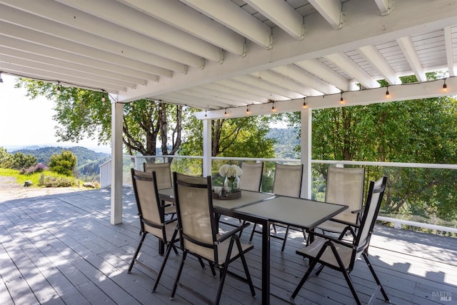 deck with a mountain view and outdoor dining area