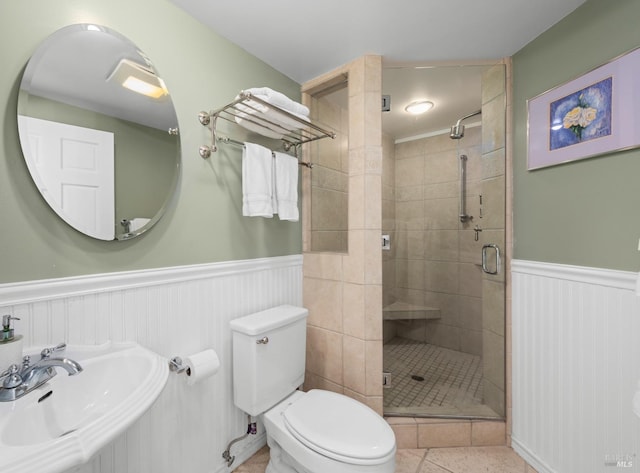 full bath with a sink, wainscoting, toilet, and a shower stall